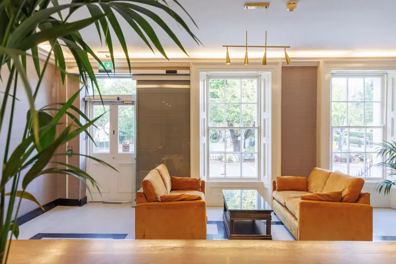 Mustard sofas and a coffee table between tall sash windows