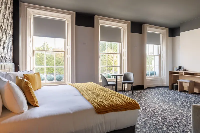 A Deluxe Family room with three tall sash windows and a super king bed