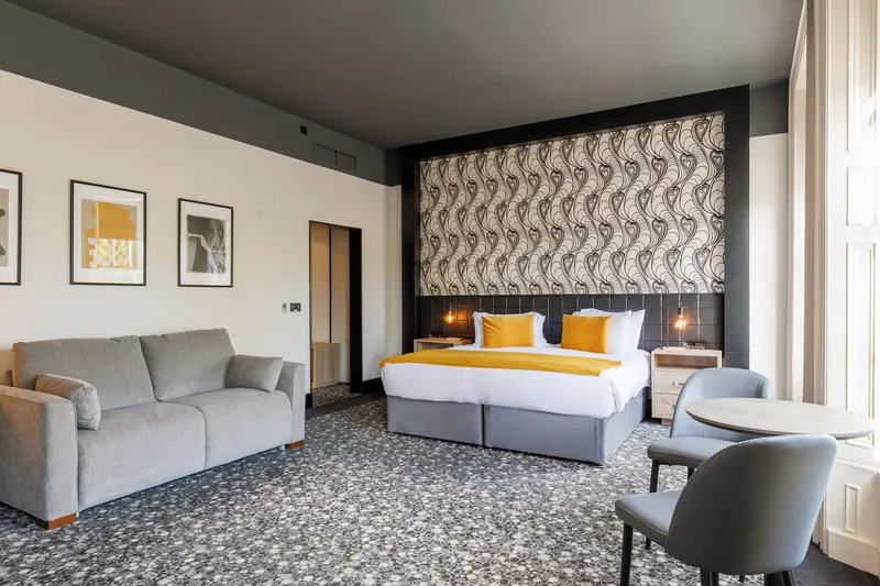 A Deluxe Family room with a super king bed, a sofa bed and a small table by the window